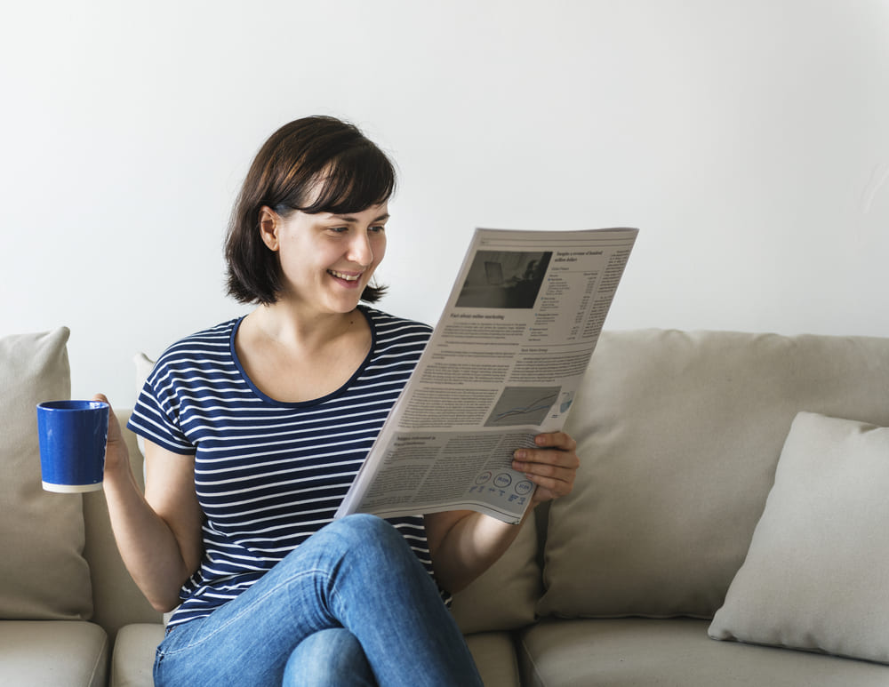 Kobieta czytająca artykuł w internecie na temat cech kawy bezkofeinowej. 